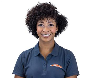 professional woman with dark curly hair smiling against a white backdrop 