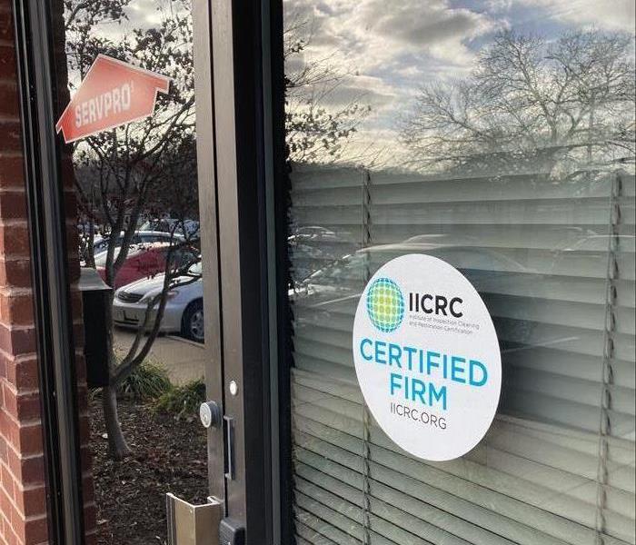 Picture of front door of office with a white IICRC certified sticker and an orange SERVPRO sticker on it.